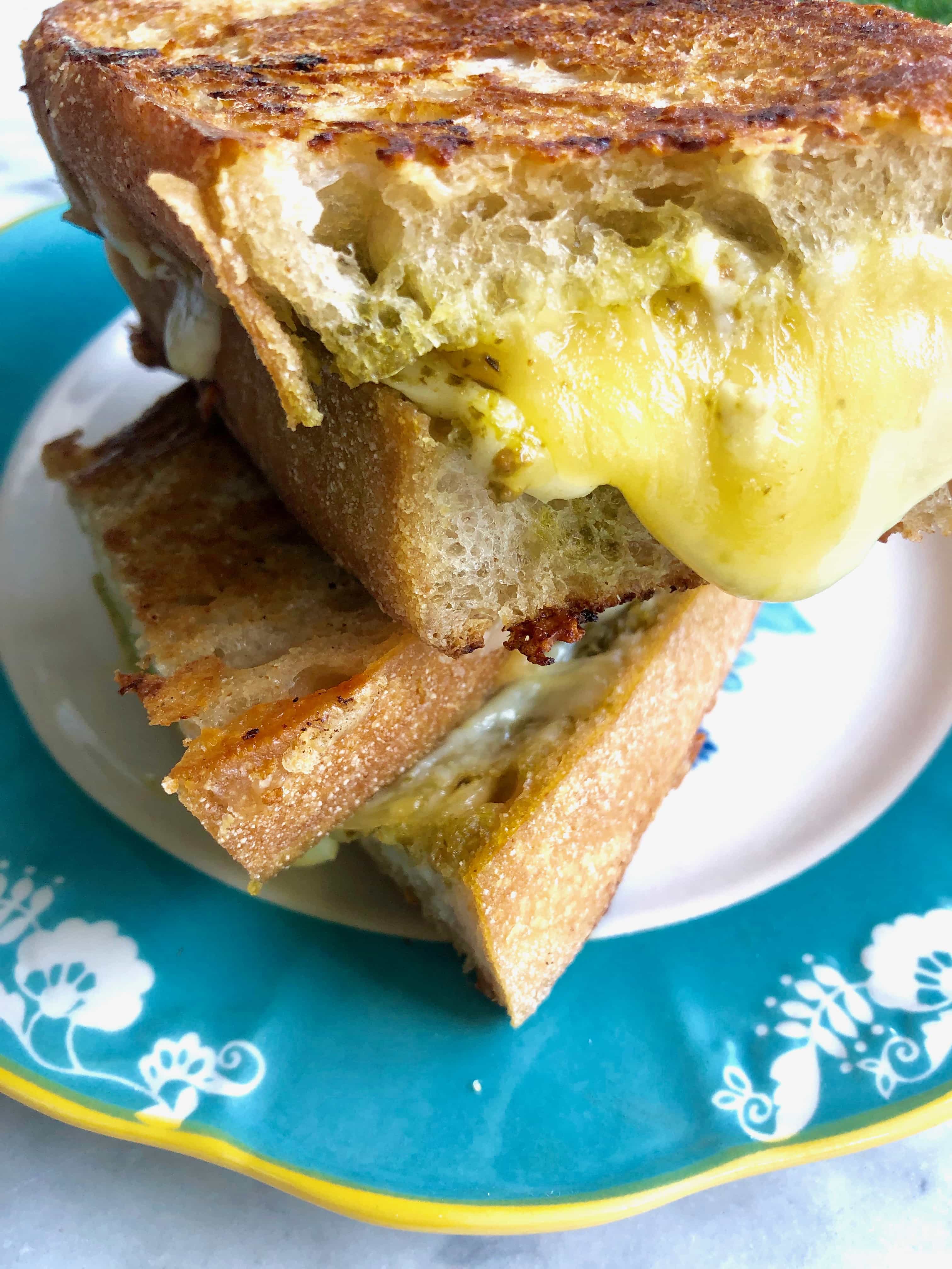grilled cheese sandwich stacked on a blue plate with cheese dripping out of it