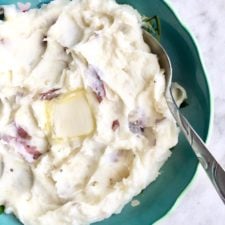 garlic mashed potatoes in a blue bowl on white background