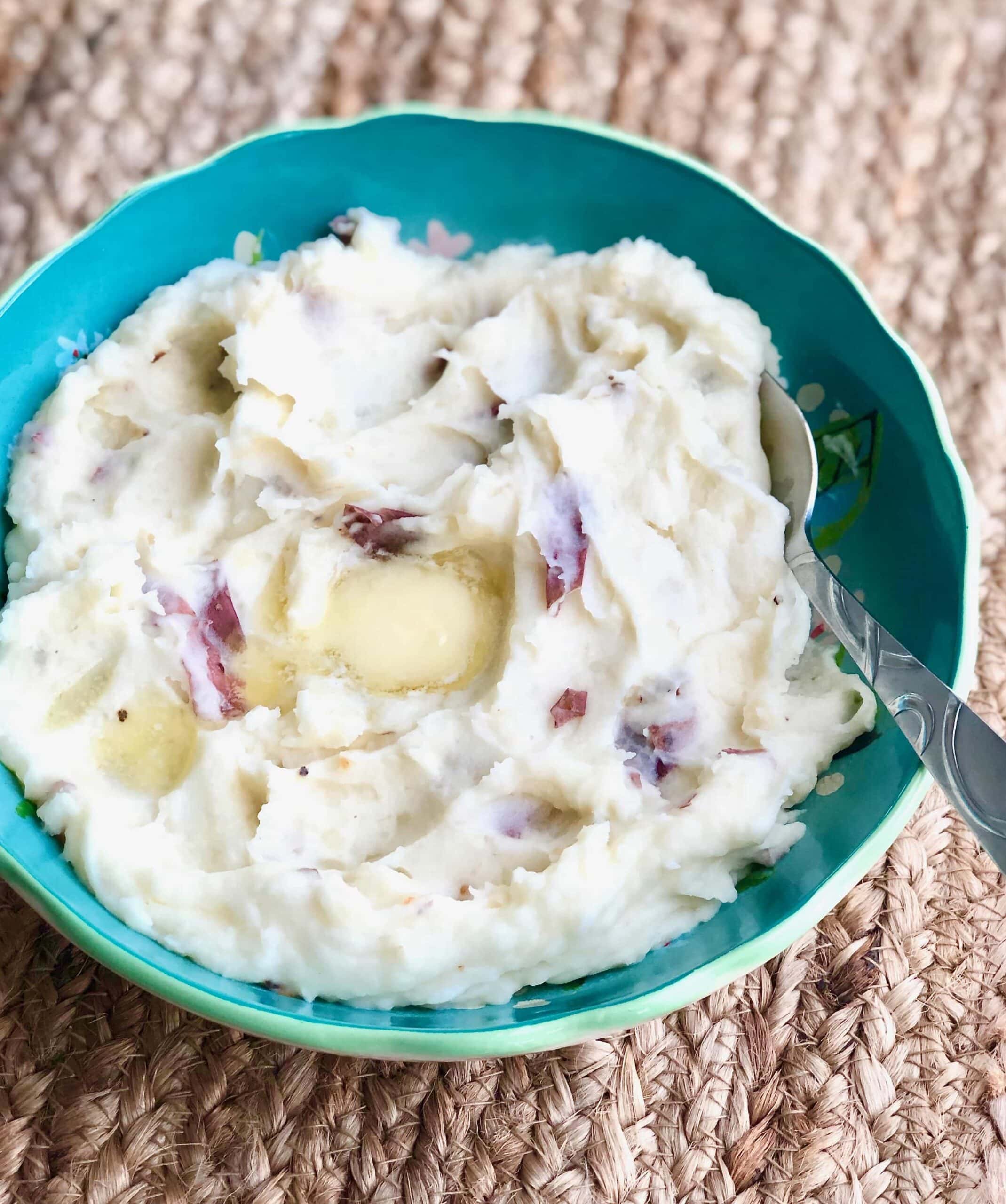 garlic mashed potatoes in a blue bowl with a pat of butter melting in the middle