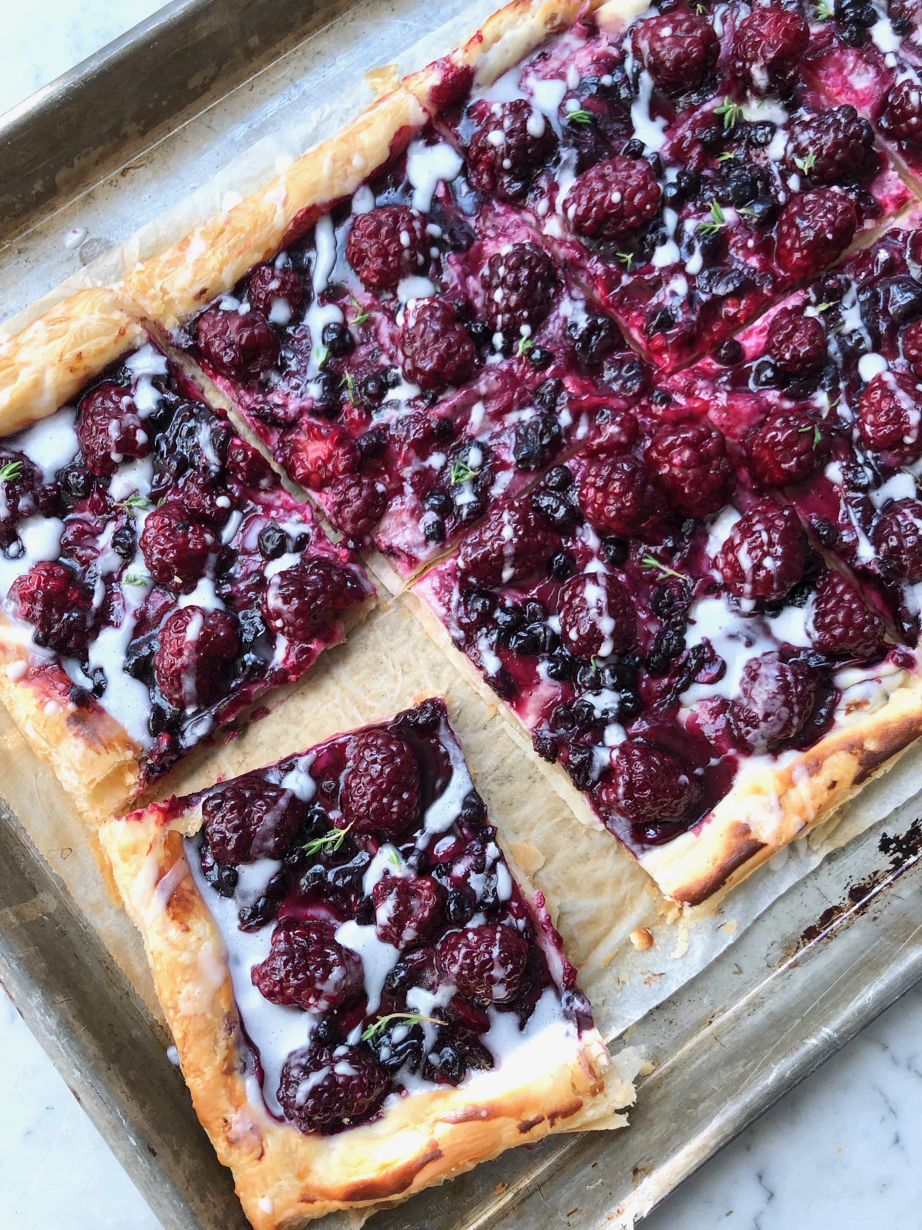 blackberry danish in puff pastry with a slice cut on a sheet pan