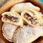twice baked pecan pie turnovers on wooden serving plates with powdered sugar
