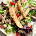 steak and potato salad on a white plate