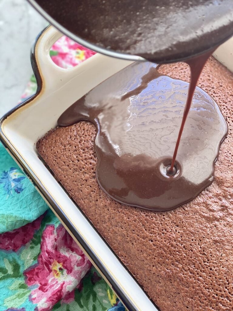 chocolate frosting being poured on top of a hot chocolate cake
