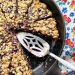 Skillet Berry Crumble in a cast iron skillet with server