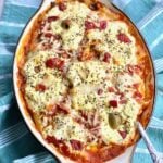 penne pasta with antipasti and sauce in a casserole dish on blue napkin