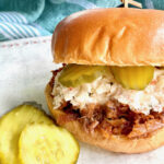 barbecue sandwich with coleslaw and pickles on a bun