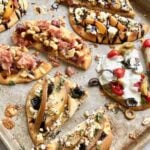 variety of pizza flatbreads cut in half on a sheet pan