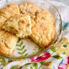 golden brown biscuits in a glass pie plate on a floral napkin