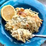 a blue plate featuring a bite of creamy lemon chicken spaghetti on a fork.