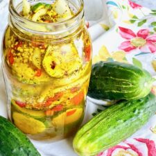 jar of bread and butter pickles with three cucumbers on a floral napkin