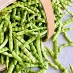 greasy cut short beans spilling out of a farmer's basket laying on its side