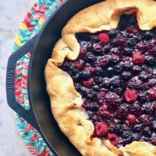 a blend of three berries in a buttery crust in a cast iron skillet