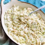 white dish filled with creamy southern coleslaw on a blue napkin