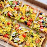 taco toppings on top of a puff pastry crust on a sheet pan.