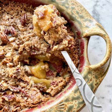 spoon holding up apple pecan crunch out of bowl.