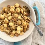 a blue bowl full of oyster cracker candy on a multi colored napkin.