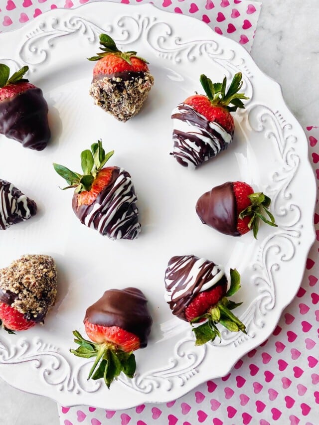 arrangement of chocolate covered berries on a white decorative plate.