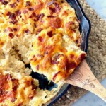 hash brown casserole in a cast iron skillet with a wooden spoon