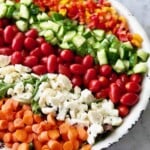 rainbow salad with carrots, cauliflower, tomatoes, cucumbers and peppers in rows.