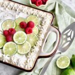key lime poke cake with lime spices and raspberries on top.