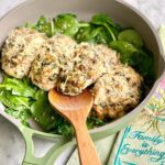 stuffed chicken breasts on a bed of spinach in a green skillet.