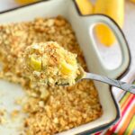 a spoon being lifted up over a squash casserole showing ingredients.