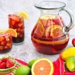 pitcher of strawberry orange sangria poured into two glasses filled with ice.