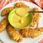 circle of buttermilk chicken tenders around a bowl of honey mustard sauce.