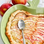 puff pastry apple tart in a green apple dish with a spoon on top.