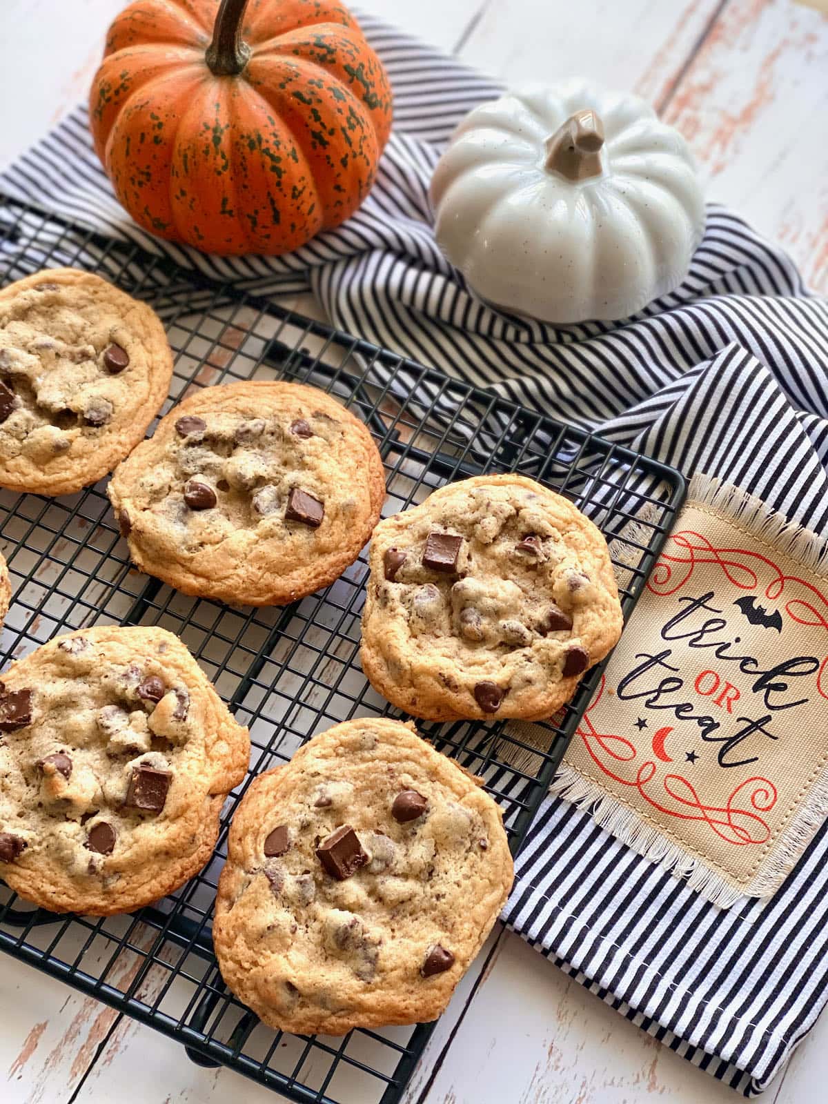 cookies cooling on a black rack with pumpkins in the background.