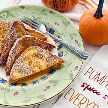 slices of pumpkin spice french toast on a green plate with pumpkins in the background.