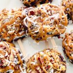 german chocolate caramel apple slices stacked on a white plate.