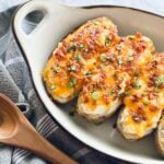 a row of potatoes topped with bacon, green onions and cheese that have been baked twice.