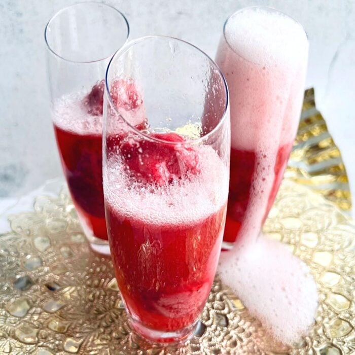 three raspberry mimosas made with raspberry sorbet and champagne.