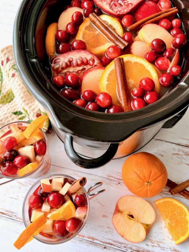 crockpot of cider filled with fruit and cinnamon.