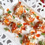 buffalo chicken meatballs made in an air fryer on a white plate with toothpicks.