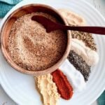 dry rub in a wooden bowl that shows spices on a white plate.