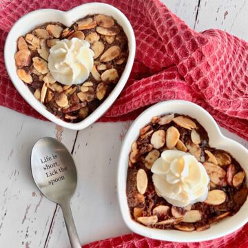 chocolate cherry cobbler in heart shaped ramekins with a silver spoon.