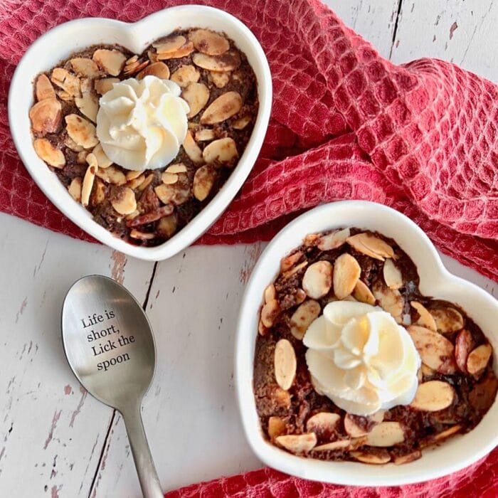 chocolate cherry cobbler in heart shaped ramekins with a silver spoon.