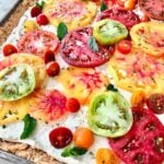 heirloom tomato tart on a sheet pan with red, blue and yellow tomatoes.