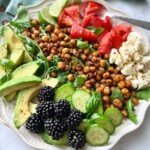 roasted chickpea salad with tomatoes, avocado and feta on a white plate.