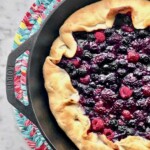 three berries in a crostata pie crust in a cast iron skillet.