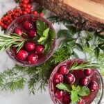 two glasses of non-alcoholic beverage with rosemary and cranberries.