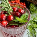 a glass of non-alcoholic Christmas punch with cranberries and mint.