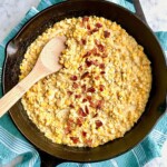 Cast Iron Skillet Creamed Corn in a black skillet with a wooden spoon.