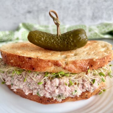old fashioned ham salad as a filling for a sandwich with a pickle on top.