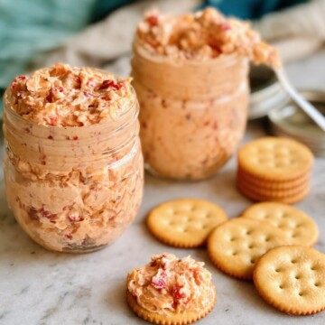 mason jars filled with old fashioned pimento cheese spread with crackers on the side.