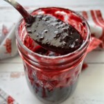 blueberry bbq sauce in a mason jar being lifted out by a spoon.