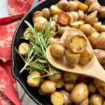 spoon holding up smoked potatoes from a cast iron skillet.