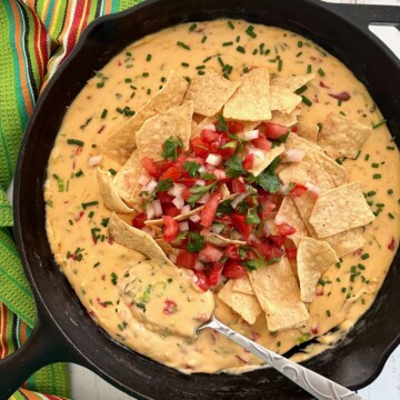 cast iron skillet filled with smoked queso dip on a traeger smoker.